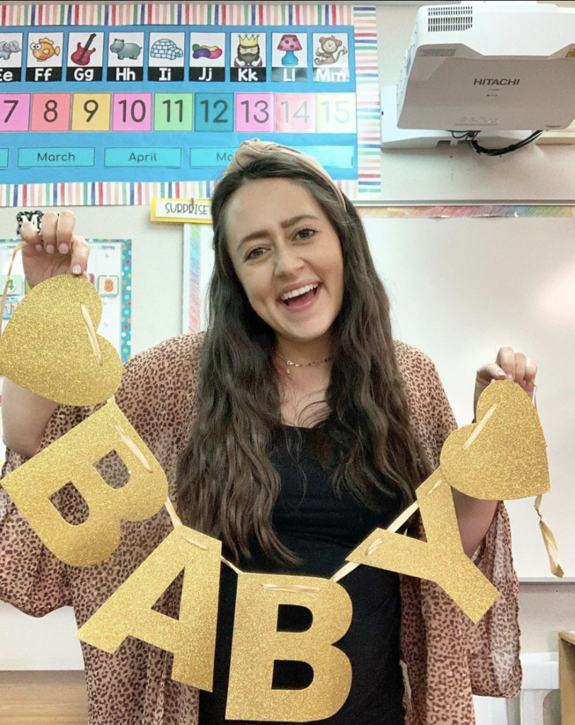 image featuring teacher holding a sign that says baby